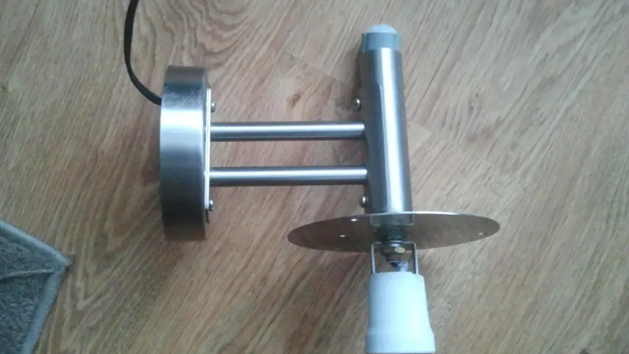 Metalowa lampa z czujnikiem ruchu, która zapala się i gaśnie, zamontowana na drewnianej podłodze.