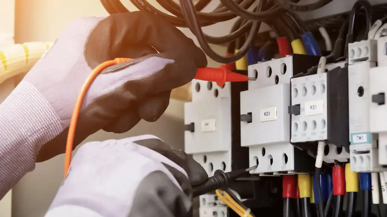 Elektryk w rękawicach sprawdza instalację, by dowiedzieć się, jak sprawdzić moc przyłączeniową.
