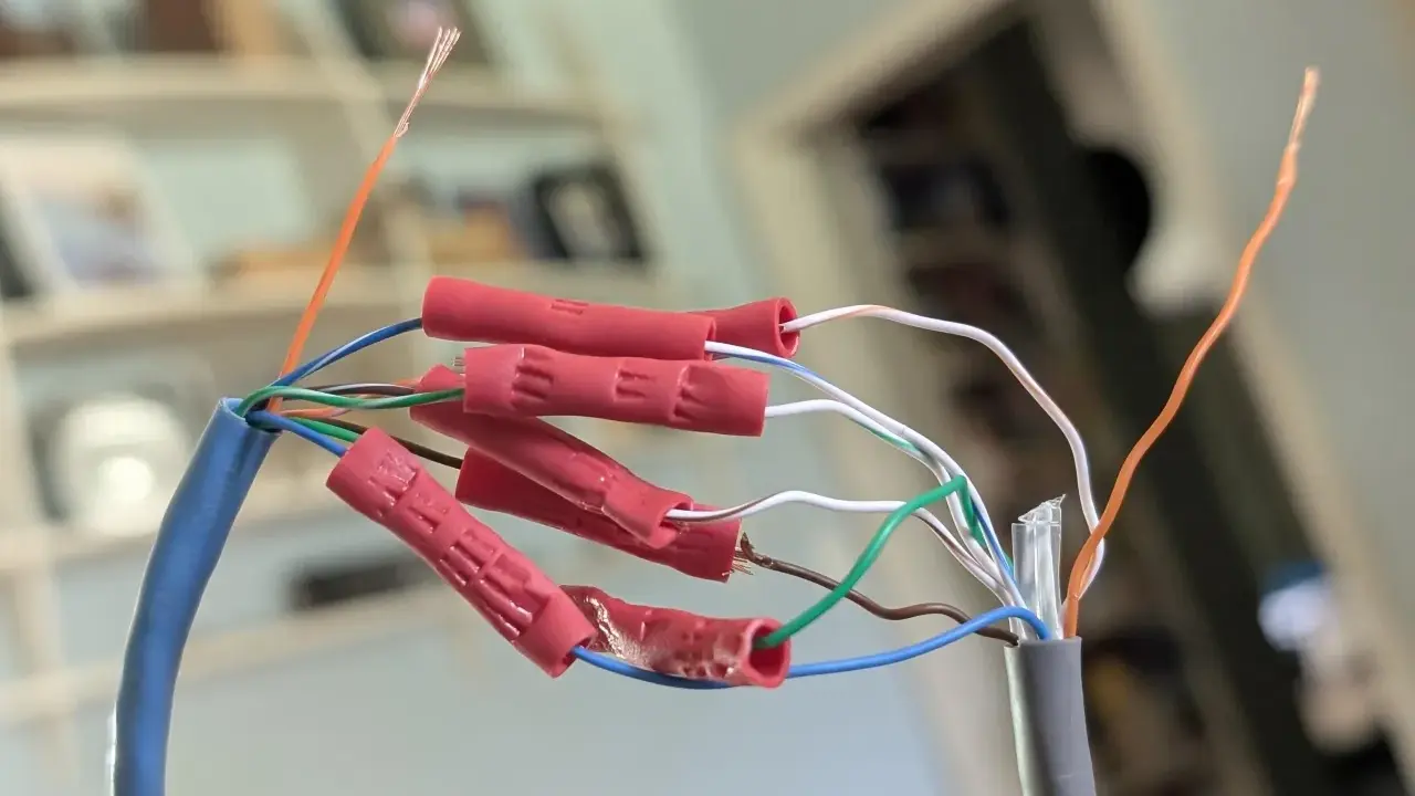Połączenie przewodów sieciowych, aby przedłużyć kabel internetowy. Czerwone złączki zaciskowe łączą żyły.