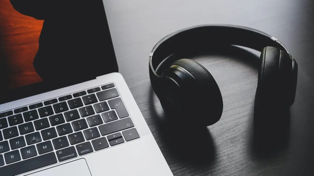Słuchawki leżą obok laptopa, który ma problem z dźwiękiem.