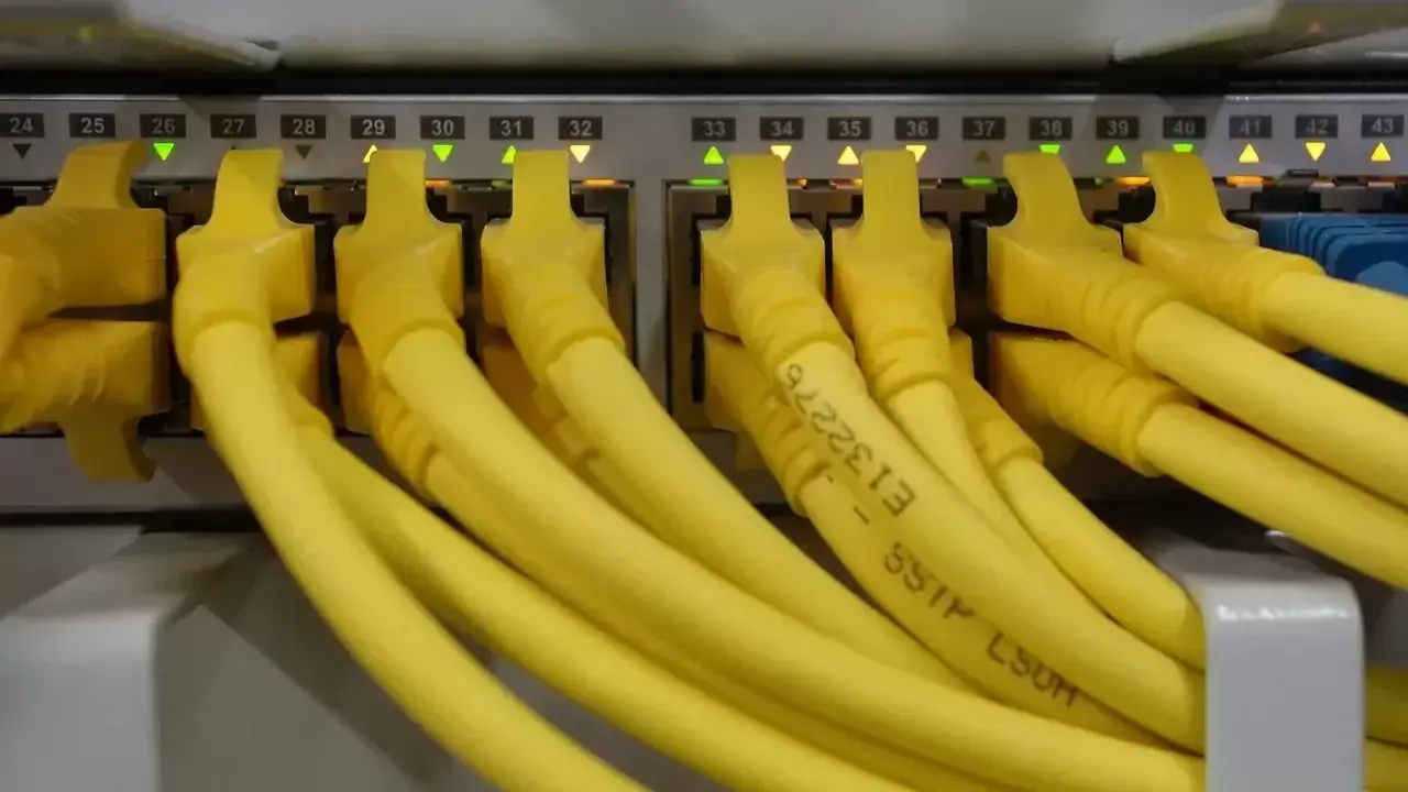 Żółte kable RJ45 podłączone do portów sieciowych, z podświetlonymi diodami. Kolejność portów od 24 do 43.