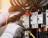 Elektryk w rękawicach sprawdza instalację, by dowiedzieć się, jak sprawdzić moc przyłączeniową.
