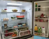 Wnętrze lodówki z drzwiami typu french door: jajka, arbuza, warzywa, słoiki z przetworami, sosy i napoje.