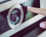 Palec naciska ikonę widelca i noża na panelu piekarnika Samsung Dual Cook. Widoczne symbole na piekarniku Samsung Dual Cook.