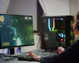 Graczka w słuchawkach gra w grę FPS, co to za gatunek? Komputer z kolorowym podświetleniem.