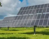 Rzędy paneli fotowoltaicznych tworzą farmę fotowoltaiczną 1 MW, która czerpie energię ze słońca na zielonej łące.