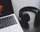 Słuchawki leżą obok laptopa, który ma problem z dźwiękiem.