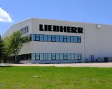 Fabryka Liebherr, gdzie produkowane są lodówki, to nowoczesny budynek z dużymi oknami i logo firmy.