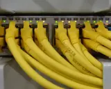 Żółte kable RJ45 podłączone do portów sieciowych, z podświetlonymi diodami. Kolejność portów od 24 do 43.