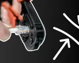 Dłoń zaciska wtyczkę RJ45 za pomocą narzędzia, pokazując, jak zacisnąć rj45.