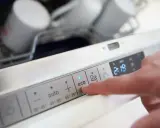 Palec naciska przycisk "eco" na panelu zmywarki, sugerując wybór programu oszczędzającego wodę.