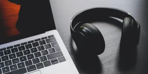 Słuchawki leżą obok laptopa, który ma problem z dźwiękiem.