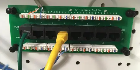 Panel sieciowy CAT 6 z ośmioma portami RJ45. Widoczne kable sieciowe i złącza.