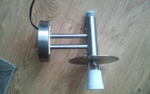 Metalowa lampa z czujnikiem ruchu, która zapala się i gaśnie, zamontowana na drewnianej podłodze.