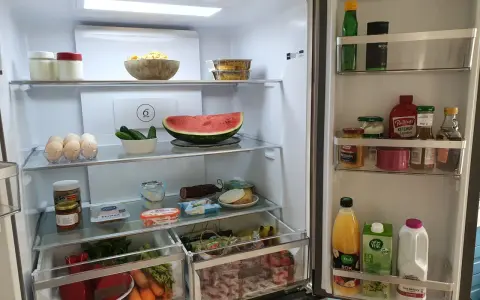 Wnętrze lodówki z drzwiami typu french door: jajka, arbuza, warzywa, słoiki z przetworami, sosy i napoje.