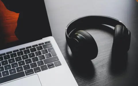 Słuchawki leżą obok laptopa, który ma problem z dźwiękiem.