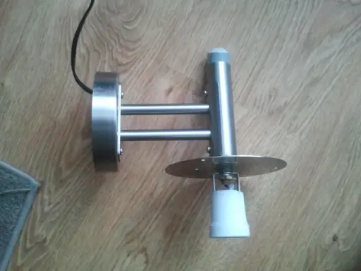 Metalowa lampa z czujnikiem ruchu, która zapala się i gaśnie, zamontowana na drewnianej podłodze.