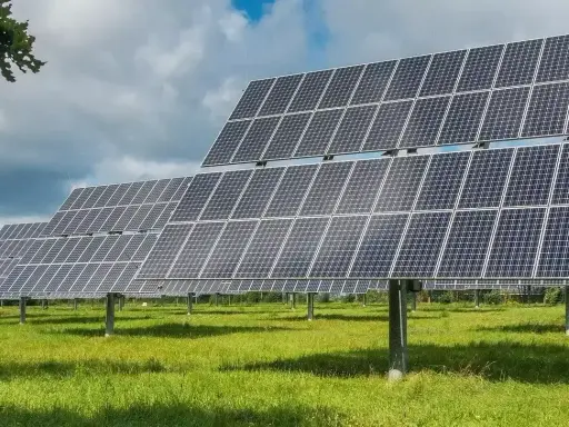 Rzędy paneli fotowoltaicznych tworzą farmę fotowoltaiczną 1 MW, która czerpie energię ze słońca na zielonej łące.