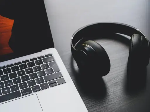 Słuchawki leżą obok laptopa, który ma problem z dźwiękiem.