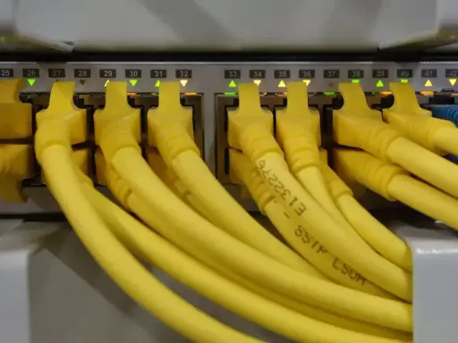 Żółte kable RJ45 podłączone do portów sieciowych, z podświetlonymi diodami. Kolejność portów od 24 do 43.