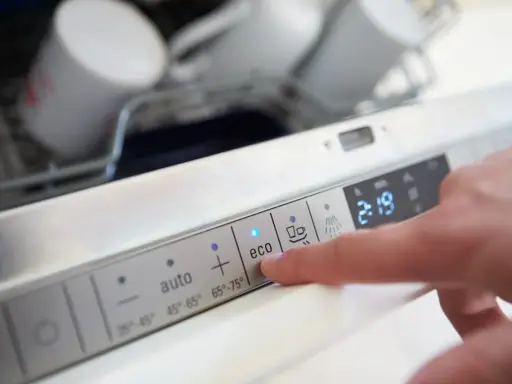 Palec naciska przycisk "eco" na panelu zmywarki, sugerując wybór programu oszczędzającego wodę.