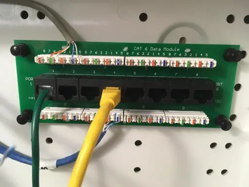 Panel sieciowy CAT 6 z ośmioma portami RJ45. Widoczne kable sieciowe i złącza.