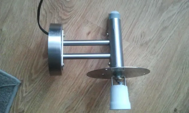Metalowa lampa z czujnikiem ruchu, która zapala się i gaśnie, zamontowana na drewnianej podłodze.