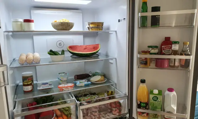 Wnętrze lodówki z drzwiami typu french door: jajka, arbuza, warzywa, słoiki z przetworami, sosy i napoje.