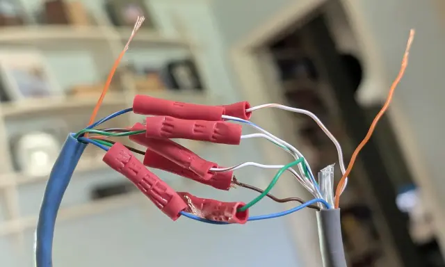 Połączenie przewodów sieciowych, aby przedłużyć kabel internetowy. Czerwone złączki zaciskowe łączą żyły.