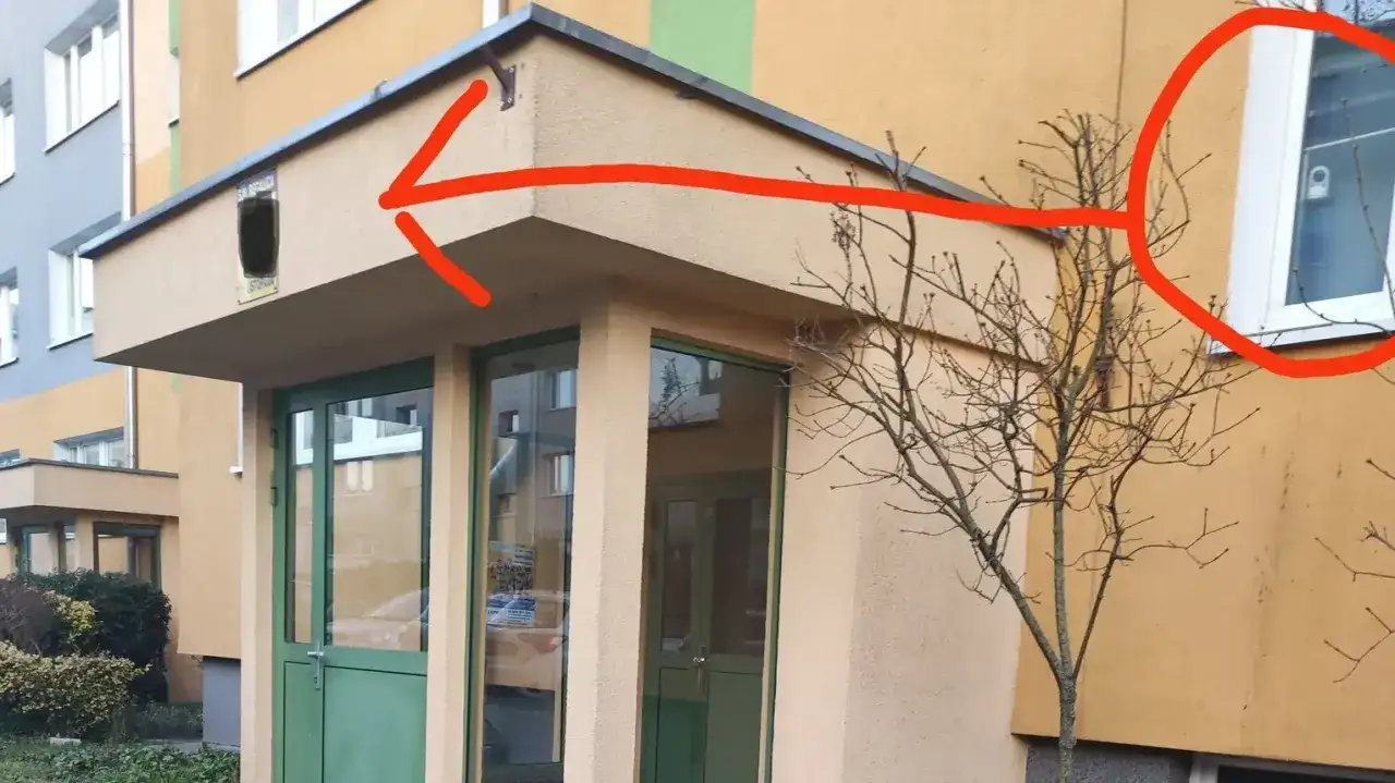 Kamery w bloku, monitoring we wsp&oacute;lnocie mieszkaniowej przepisy. Czerwona strzałka wskazuje na okno z kamerą.