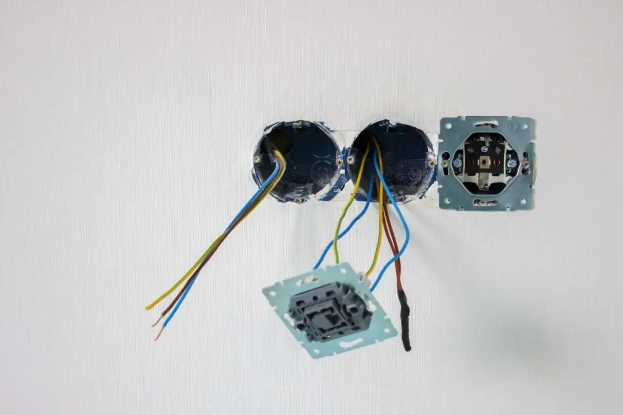 Instalacja elektryczna: puszka w styropianie z wystającymi przewodami i elementami gniazdek.