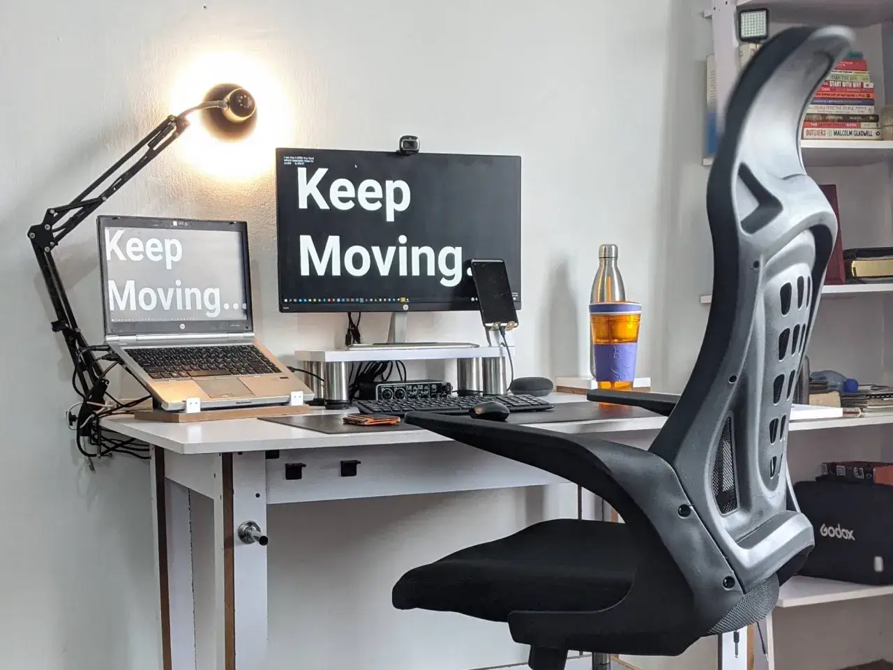 Ergonomia pracy przy komputerze: biurko z laptopem, monitorem i lampką. Napisy 