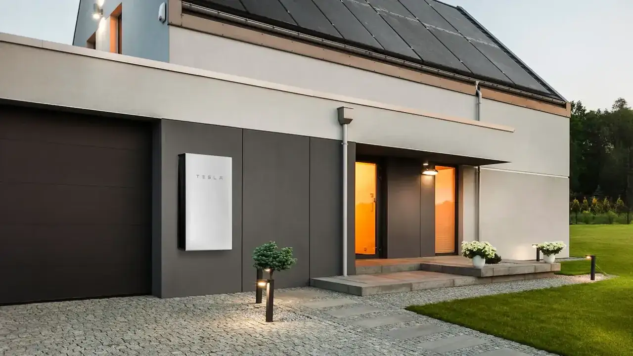 Nowoczesny dom z panelami słonecznymi na dachu i magazynem energii Tesla. To przyszłość zielonej energii.